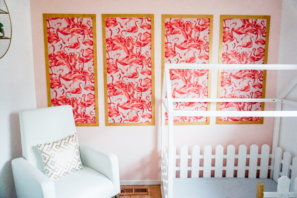 girls nursery room: flamingo wallpaper with gold frame in modern chinoiserie on a pink wall, white modern rocking chair, and white wooden house bed