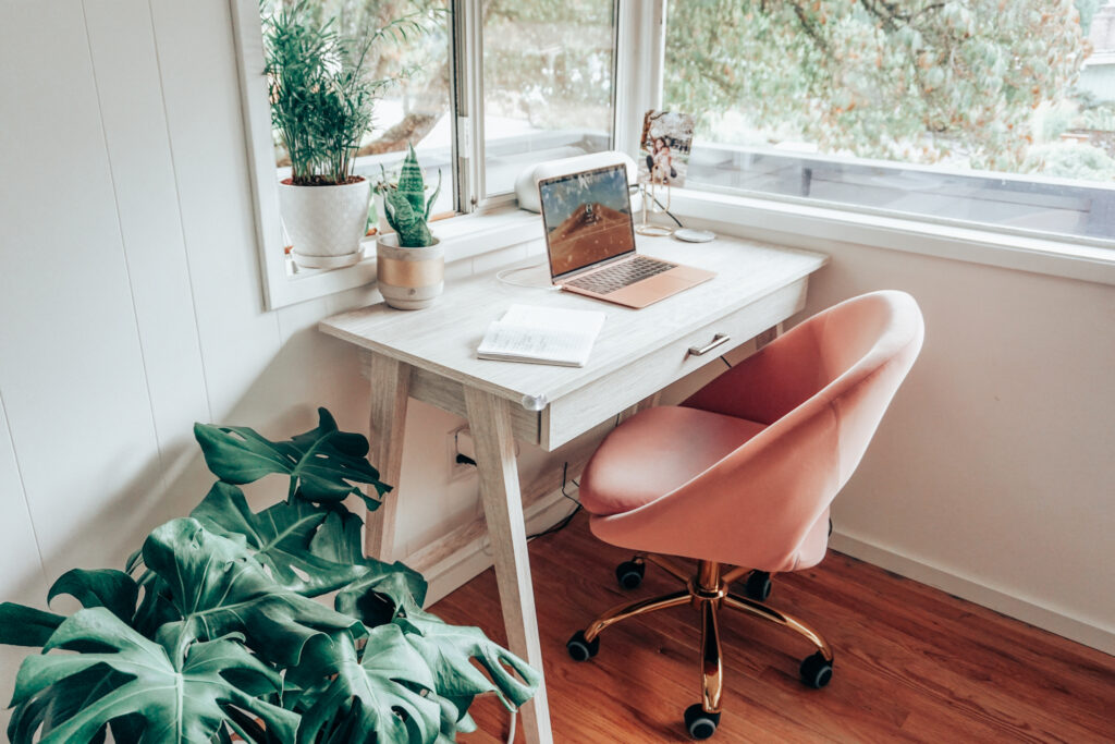 White mid century desk, pink swivel office chair, house plants
