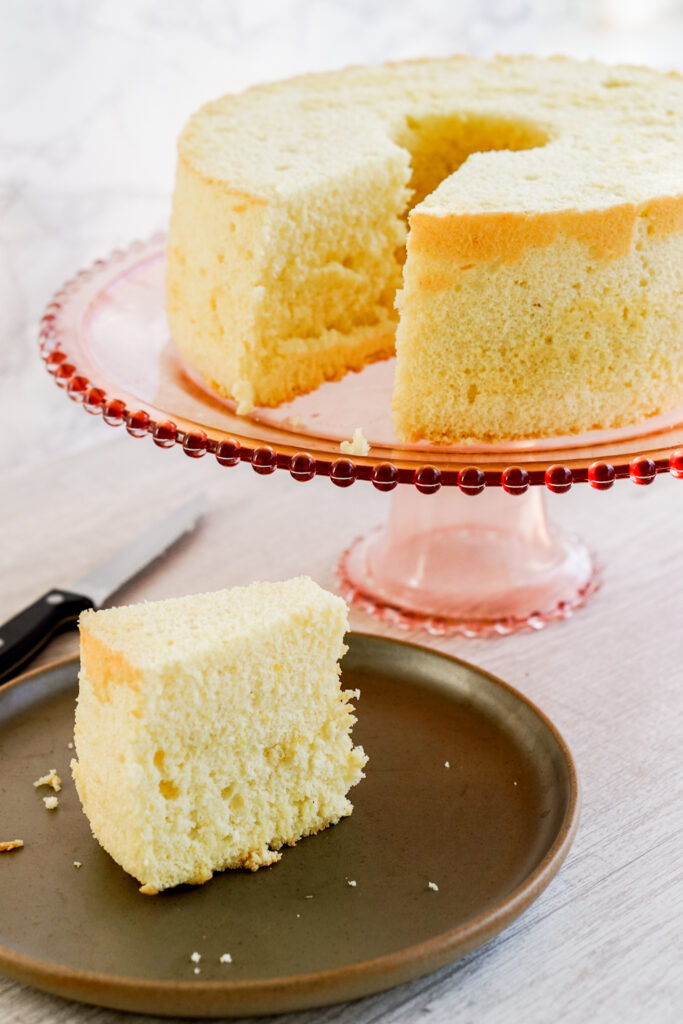 Chinese vanilla sponge cake sitting on a cake stand; one slice is on a plate.
